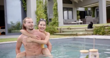 Genç beyaz bir çift evde havuz gününün tadını çıkarıyor. Kız arkadaşı, kahverengi saçlı, erkek arkadaşına arkadan sarılıyor, gülümseyerek, değişmeden, ağır çekimde.