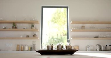 Günışığı modern bir mutfağa doluyor, temiz çizgileri fotokopi alanıyla aydınlatıyor. Açık raflar mutfak malzemeleriyle düzgünce düzenlenir. Minimalist bir titreşim yaratır. Yavaş çekim, değiştirilmemiş..