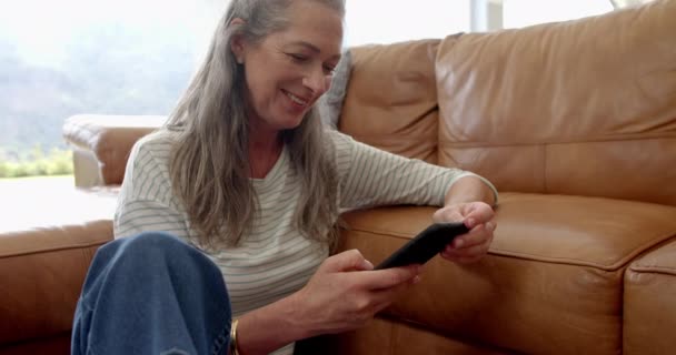 Uma Mulher Caucasiana Madura Está Envolvida Com Seu Smartphone Sofá — Vídeo de Stock