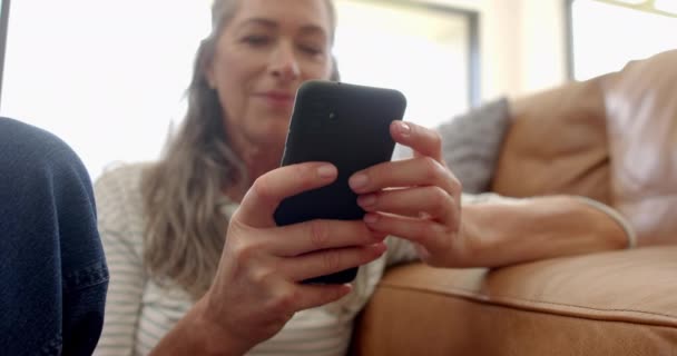 Olgun Bir Beyaz Kadın Evdeki Kanepede Akıllı Telefonuna Gülümsüyor Açık — Stok video