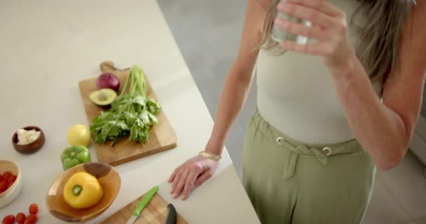 Olgun Beyaz Bir Kadın Evde Salata Yaparken Bir Mutfakta Yudumluyor — Stok video