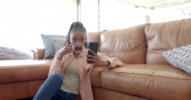 Una Joven Afroamericana Bebiendo Usando Teléfono Inteligente Con Espacio Para — Vídeo de stock