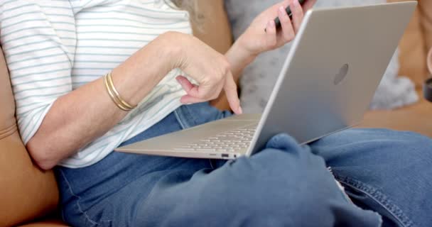 Een Volwassen Blanke Vrouw Gebruikt Thuis Een Smartphone Laptop Een — Stockvideo