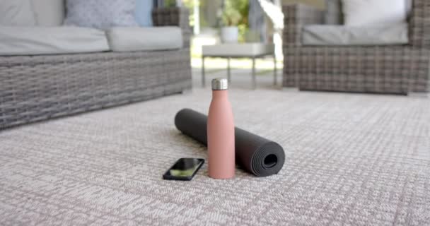 瑜伽垫和智能手机躺在有纹理的地板上 粉色背景 这些物品表明 在一个安静 光线充足 动作缓慢 没有变化的房间里 在一个健身过程中休息一下 — 图库视频影像