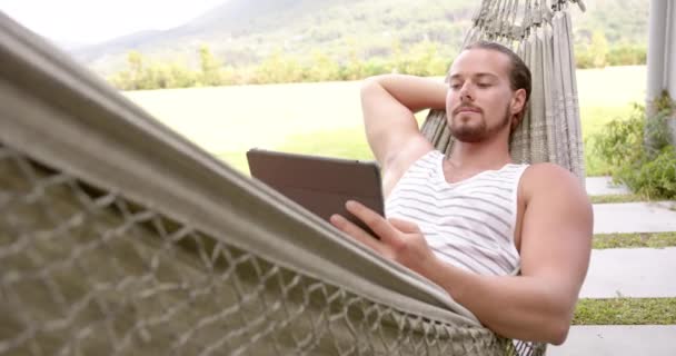 Jovem Caucasiano Relaxa Uma Rede Com Tablet Quintal Casa Ele — Vídeo de Stock