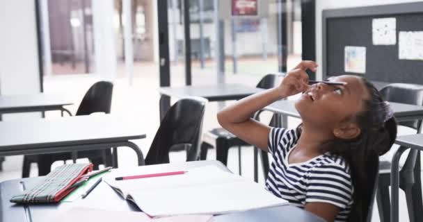 Koulussa Nuori Afroamerikkalainen Tyttö Jolla Hauskaa Istuu Kirjoituspöydän Ääressä Jossa — kuvapankkivideo