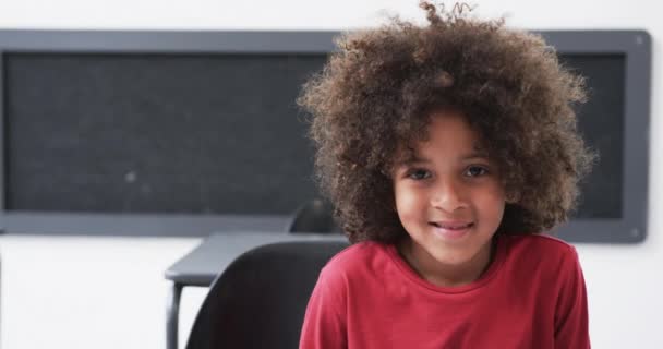 교실에서 아프리카계 미국인 소년이 따뜻하게 공간으로 미소를 짓습니다 머리카락을 가지고 — 비디오