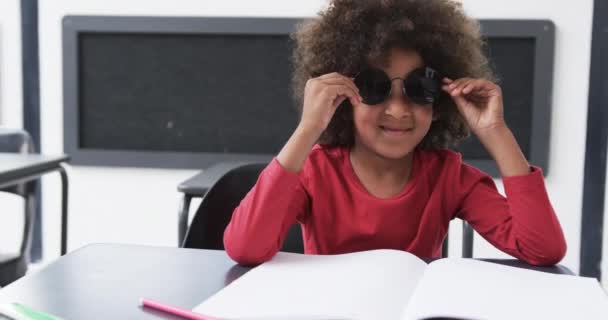 Skoleklasserom Sitter Ungt Afroamerikansk Barn Ved Skrivebord Sporting Store Solbriller – stockvideo