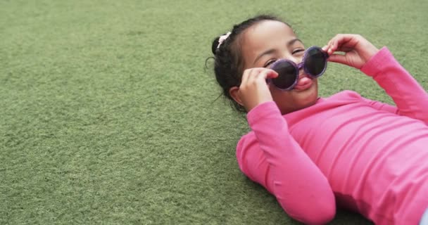Kouluympäristössä Nuori Afroamerikkalainen Tyttö Makaa Nurmikolla Kopiotilan Kanssa Hän Säätää — kuvapankkivideo