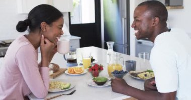 Çeşitli bir çift mutfakta birlikte kahvaltı etmekten zevk alıyor. Afrika kökenli Amerikalı koca kısa bir saç kesimine sahipken, karısı, saçları geriye çekilmiş, elinde bir kupa, değiştirilmemiş, ağır çekimde.