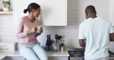 Çeşitli bir çift modern bir mutfakta sohbet etmekten zevk alır. Afrikalı Amerikalı koca, elinde beyaz bir kupayla Asyalı karısını dinliyor. Konuşurken el kol hareketi yapıyor.