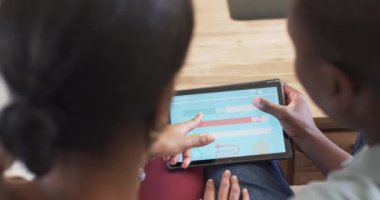 Çeşitli bir çift tablet üzerinde akıllı ev uygulaması enerji kullanımını inceliyor. Koyu renk saçlı kadın ekranı işaret ederken, erkek de siyah saçlı, gözlemci, değişmemiş, ağır çekimde....