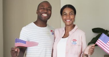 Çeşitli bir çift gururla ışıldıyor, ellerinde Amerikan bayrakları ve oy etiketleri var. Afro-Amerikalı erkek ve İspanyol kadın her ikisi de etiketler takıyor. Vatandaşlık nişanı sergiliyorlar, değiştirilmemişler.