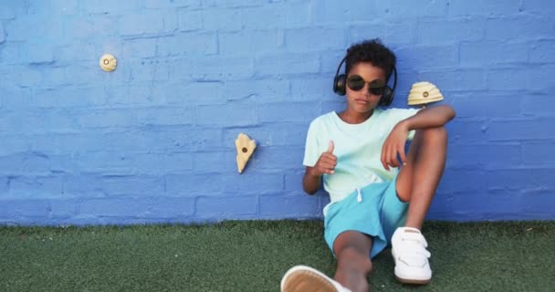 Kouluympäristössä Afroamerikkalainen Poika Rentoutuu Sinistä Seinää Vasten Kopioimalla Tilaa Hän — kuvapankkivideo