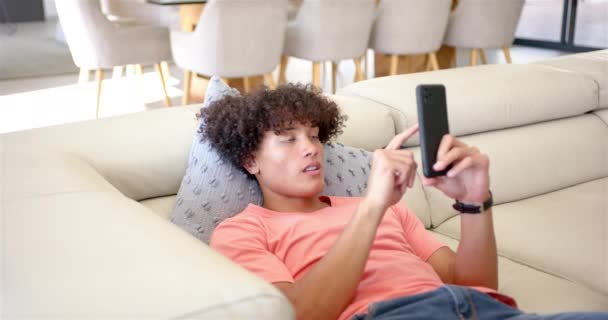 Young Biracial Man Lounging Sofa Smartphone Hand Has Curly Hair — Stock Video