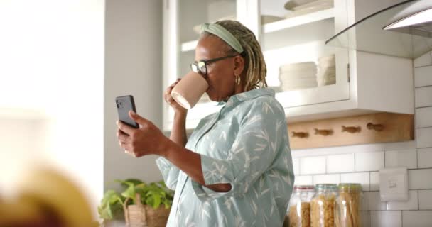 Una Donna Afroamericana Anziana Sorseggia Caffè Sfoglia Suo Smartphone Cucina — Video Stock