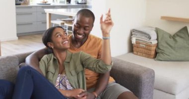 Çeşitli bir çift kanepede keyifli bir anı paylaşıyor. Afrikalı Amerikalı koca, açık tenli ve kıvırcık saçlı, değişmemiş, ağır çekimde karısına gülümsüyor.