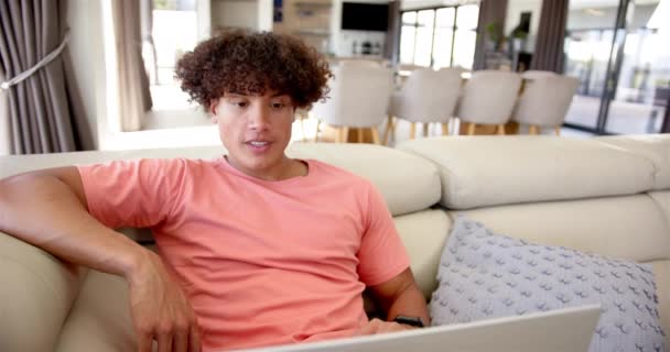 Młody Dwurasowy Mężczyzna Kręconymi Włosami Siedzi Rozmyślnie Kanapie Nosi Koszulę — Wideo stockowe