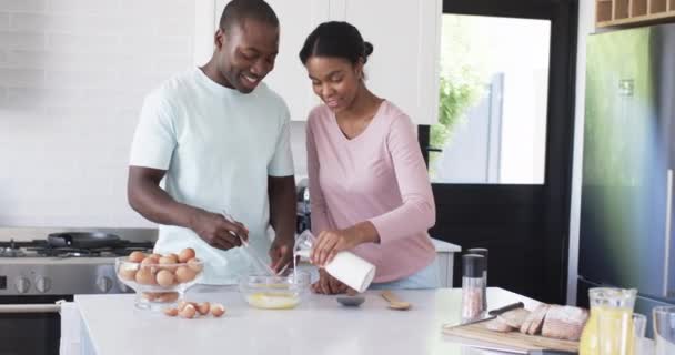 一对多样化的夫妇正在一起准备早餐 非洲裔美国人丈夫倒牛奶 而他的妻子则温和地微笑着 保持不变 动作缓慢 — 图库视频影像