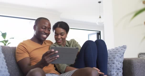 Nuori Afroamerikkalainen Pari Nauttii Tabletin Yhdessä Kotona Sohvalla Istuvat Sohvalla — kuvapankkivideo