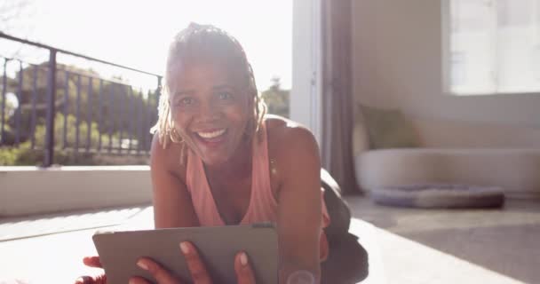 Sopiva Afroamerikkalainen Nainen Käyttää Tablettia Makaa Lattialla Kotona Hän Säteilevä — kuvapankkivideo