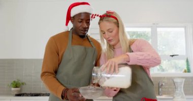 Birlikte yemek pişiriyorlar, çeşitli çiftler mutfakta Noel için hazırlanıyorlar, mutlu bir şekilde gülümsüyorlar. Yaşam tarzı, tatil, şenlik, hazırlık, yemek pişirme, neşeli