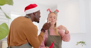 Birlikte Noel kurabiyesi süsleyen, mutfakta şenlikli şapkalar takan bir çift. Tatil, pişirme, kutlama, ev, aşçılık, ilişki