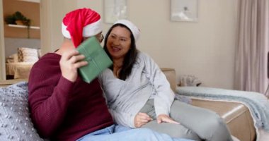 Kıdemli Asyalı çift evde hediyelerini değiş tokuş ediyor, gülümsüyor ve Noel 'in tadını çıkarıyorlar. Kutlama, tatil, aile, mutluluk, şenlik, birliktelik
