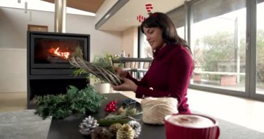 Evde Noel çelengi yapan bir kadın, bayram süslerinin tadını çıkarıyor. Kutlama, DIY