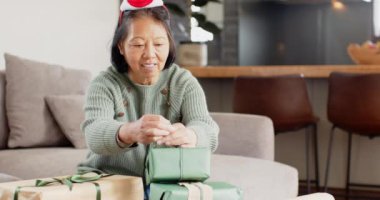 Gülümseyen son sınıf öğrencisi kadın Noel hediyelerini paketliyor, bayram sezonunun tadını çıkarıyor. tatil, neşe, kutlama, yaşlılar