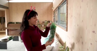 Duvarı Noel çelengiyle dekore eden kadın, neşeli bir ortam yaratıyor. Tatil, dekorasyon, süs, kutlama, mevsimlik, kış