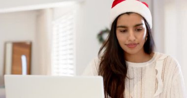 Noel zamanı, Hintli bir kadın evde kredi kartıyla Noel Baba şapkası alışverişi yapıyor. Noel, e-ticaret, şenlik, dijital alışveriş, kış tatili, alışveriş