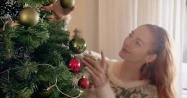Gülümseyen kadın Noel ağacını süslerle süslüyor, kendini neşeli hissediyor. Dekorasyon, bayram, kutlama, eğlence, gelenek, mevsimlik