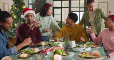 Noel 'i birlikte kutlayan, neşeli yemek ve kahkahaların tadını çıkaran farklı genç arkadaşlar. Parti, tatil, kutlama, arkadaşlık, akşam yemeği, ziyafet