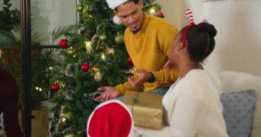 Çeşitli arkadaşlar hediye alışverişi yapıyor ve şenlik toplantısında Noel ağacı yakınında gülüyorlar. Kutlama, arkadaşlık, tatil, parti, hediye, kış