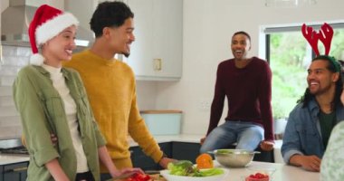 Noel 'i kutluyoruz, çeşitli arkadaşlar mutfaktaki şenlikli dekorasyonla birlikte gülüyorlar. Tatil, kutlama, arkadaşlık, kış, yemek, neşe