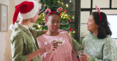 Noel 'i evde kutlayan, gülen ve ağacın yanında kadeh kaldıran genç arkadaşlar. Kutlama, tatil, şenlik, arkadaşlık, parti, neşe