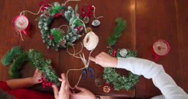 Birlikte Noel çelengi yapmak, sıcak kakaonun ve şenlikli dekorasyonun tadını çıkarmak. Tatil, aile, kutlama, sıcaklık, gelenekler, mevsimlik