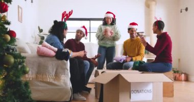 Noel 'de, çeşitli şapkalar takan genç arkadaşlar evde bağış için kıyafet paketliyorlar. gönüllü olmak, hayır işi, vermek, topluluk, cömertlik, birlikte