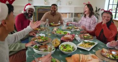 Çeşitli aileler Noel yemeğinin tadını çıkarıyor, birlikte gülüyor ve neşeli anları paylaşıyorlar. Kutlama, gelenek, tatil, birliktelik, mutluluk, ziyafet