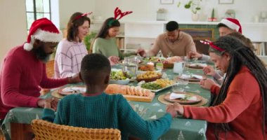 Çeşitli aileler Noel yemeğini birlikte yiyor, kahkaha ve neşeyi paylaşıyorlar. Kutlama, tatil, toplanma, birliktelik, gelenek, topluluk