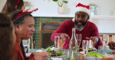 Çeşitli aileler Noel yemeğini birlikte kutluyor, gülüyor ve bayram yemeğinin tadını çıkarıyor. Kutlama, tatil, gelenek, kahkaha, ziyafet