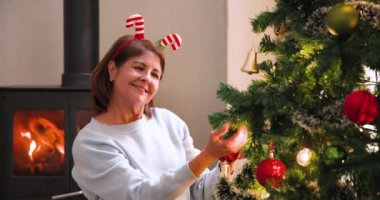 Noel ağacı süslemek, şöminenin yanında gülümseyen, bantlı bir kadın. tatil, kutlama, gelenek, neşe, dekorasyon, kış