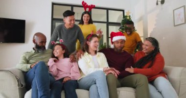 Çeşitli aileler Noel 'i evde kutluyor, ağaçta birlikte gülüyorlar. Kutlama, tatil, birliktelik, mutluluk, şenlik, gelenek