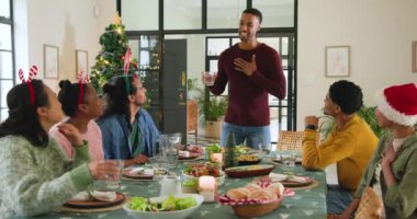 Çeşitli arkadaşlar Noel 'i evde kutluyor, şenlik masasında gülüyor ve kadeh kaldırıyorlar. Kutlama, tatil, akşam yemeği, arkadaşlık, tezahürat, toplantı