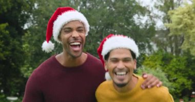 Noel 'de, çeşitli genç arkadaşlar Noel Baba şapkaları takıp açık havada neşeli bir şekilde gülüyorlar. Tatil, Noel, kutlama, birliktelik, arkadaşlık, mutluluk