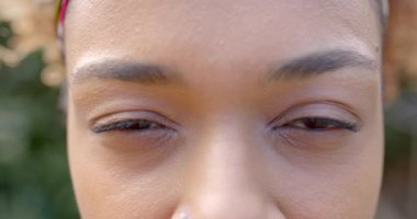 Mutlu Afro-Amerikan kadın portresi kameraya bakıyor, bahçede gülümsüyor, ağır çekimde. Yaşam tarzı, sonbahar ve eğlence, değiştirilmemiş.