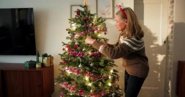 Son sınıf öğrencisi kadın Noel ağacını süslerle süslüyor, neşeli hissediyor. bayram, kış, kutlama, şenlik, dekorasyon, gelenek