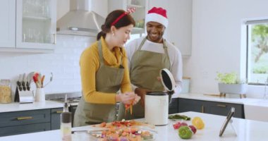 Noel 'de, festival yemeği hazırlarken, mutfakta tatil temalı aksesuarlar takan bir çift. Yemek pişirme, kutlama, tatiller, aile, ev hayatı, hazırlık