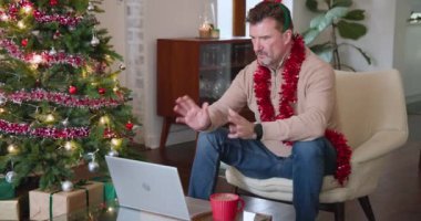 Noel 'de, evde dizüstü bilgisayarla sohbet eden yaşlı bir adam festival süslemeleri takıyor. Teknoloji, iletişim, bağlantı, yaşlılık, yaşam tarzı, kutlama